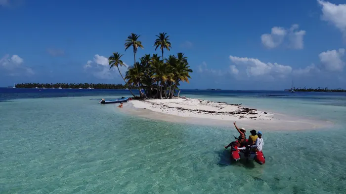 Dinghy arriving at a tiny palm island in San Blas