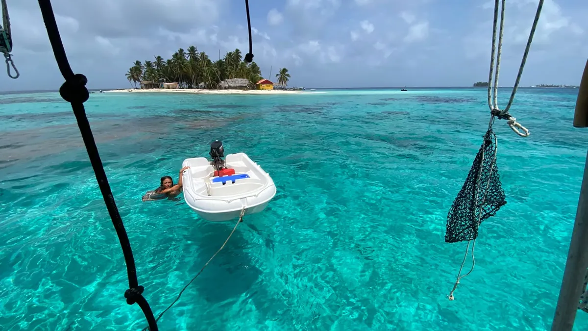 Swimming next to the dinghy in turquoise water, seen from the sailboat