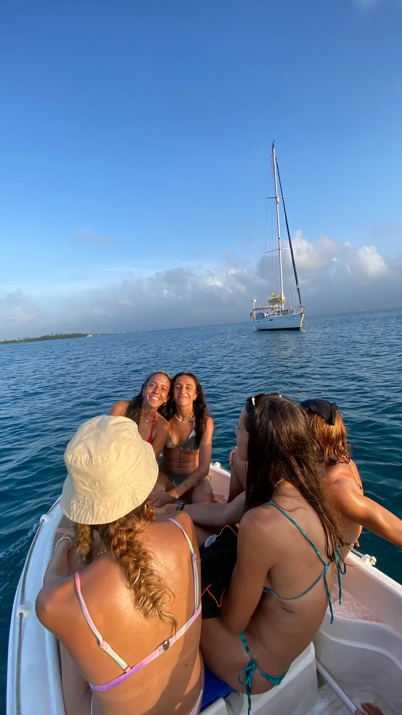 Friends in the dinghy with the sailboat anchored behind them