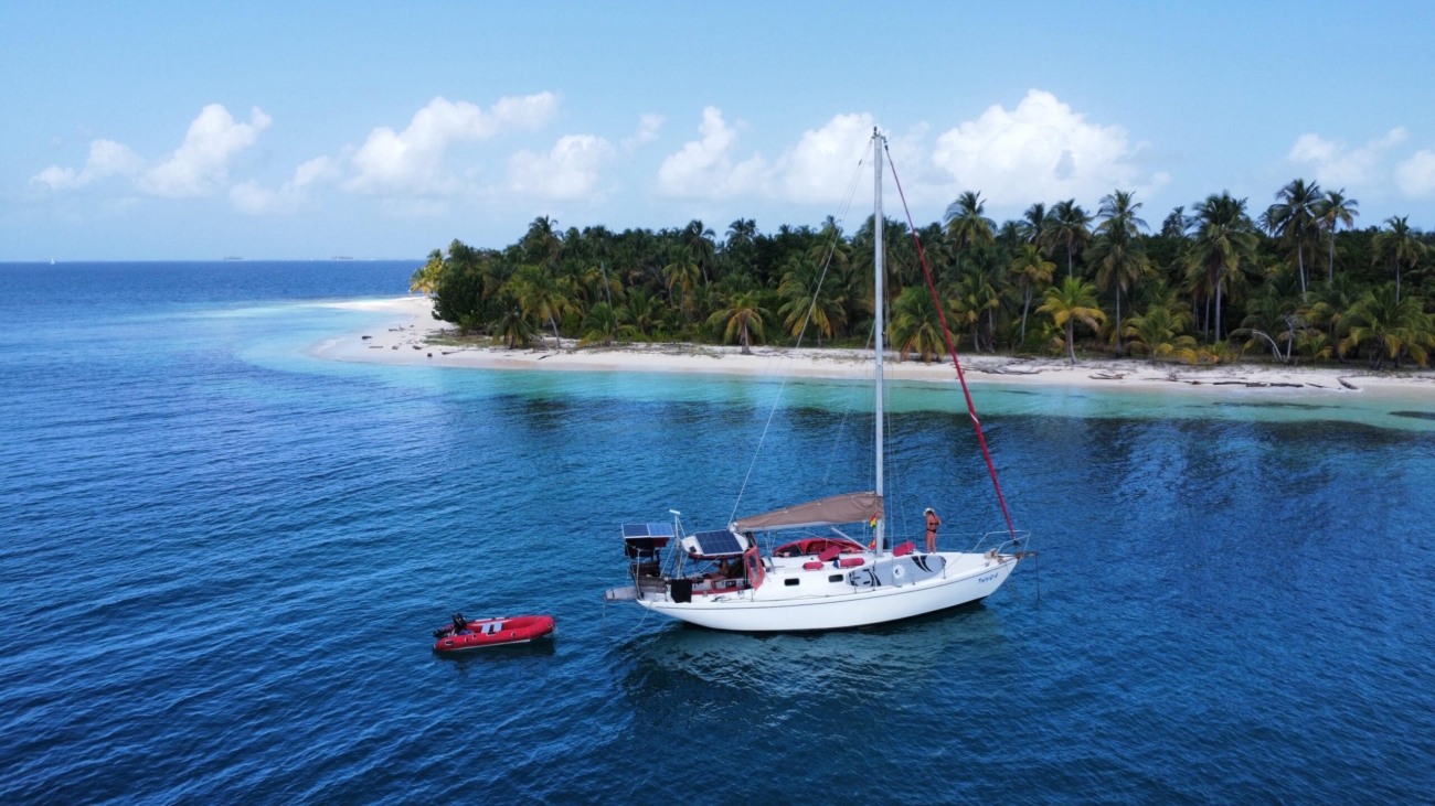 Sailboat anchored off lush green island in the San Blas region of Panama