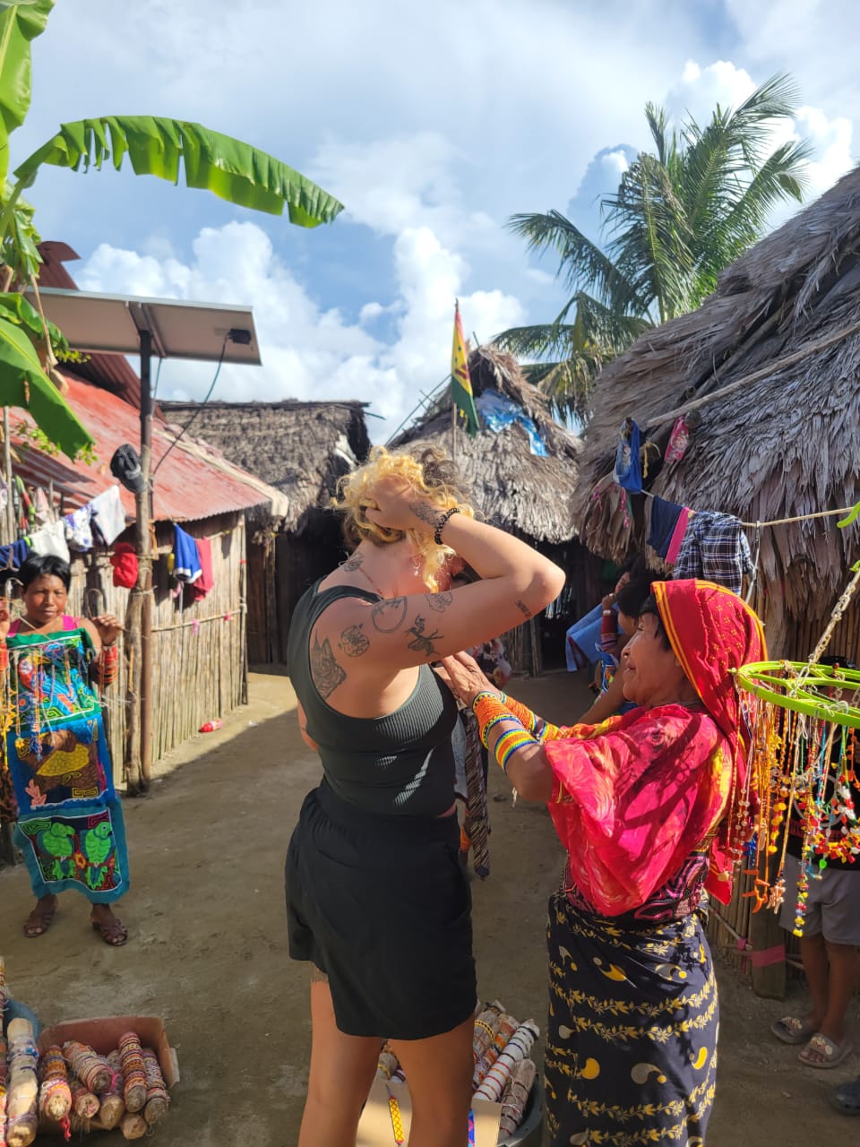 Local Guna woman helping tourist wear traditional handmade jewelry in a village in San Blas