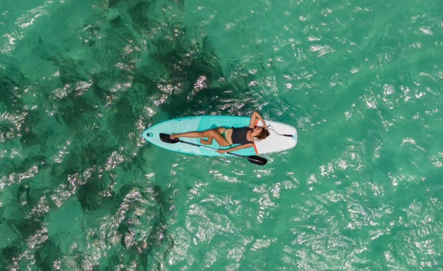 Woman paddleboarding over shallow coral reef in clear turquoise waters near San Blas