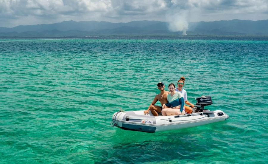 Family riding an inflatable dinghy on calm Caribbean sea with dramatic clouds in the distance