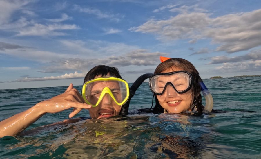 Couple with snorkel masks smiling above water during tropical sailing adventure
