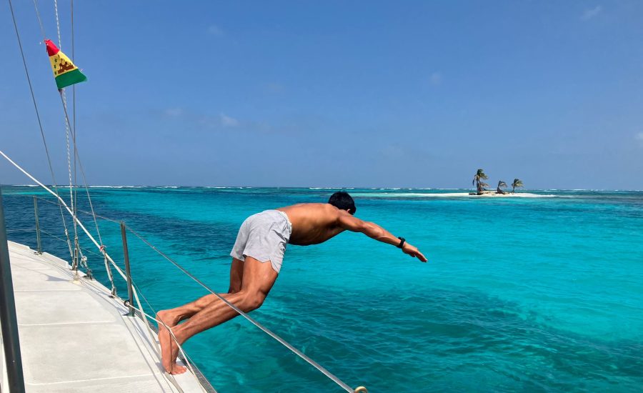 Man diving off a catamaran into crystal-clear turquoise water in the San Blas Islands