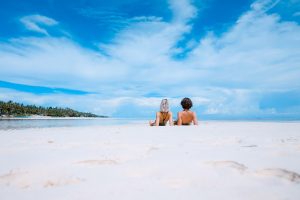 Couple relaxing on the beach with the view of a private sailing boat at sunset in San Blas